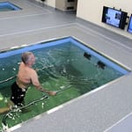 man walking assisted by rails in pool for integrated water physical therapy