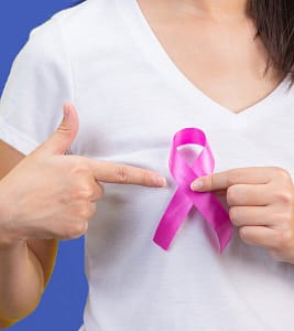 Ozone Therapy can help treat breast cancer. Image of woman holding breast cancer ribbon over white T-shirt