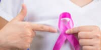 Ozone Therapy can help treat breast cancer. Image of woman holding breast cancer ribbon over white T-shirt