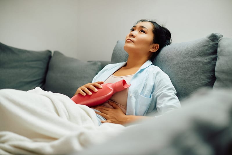 woman with pelvic pain using a hot water bottle to help with pain